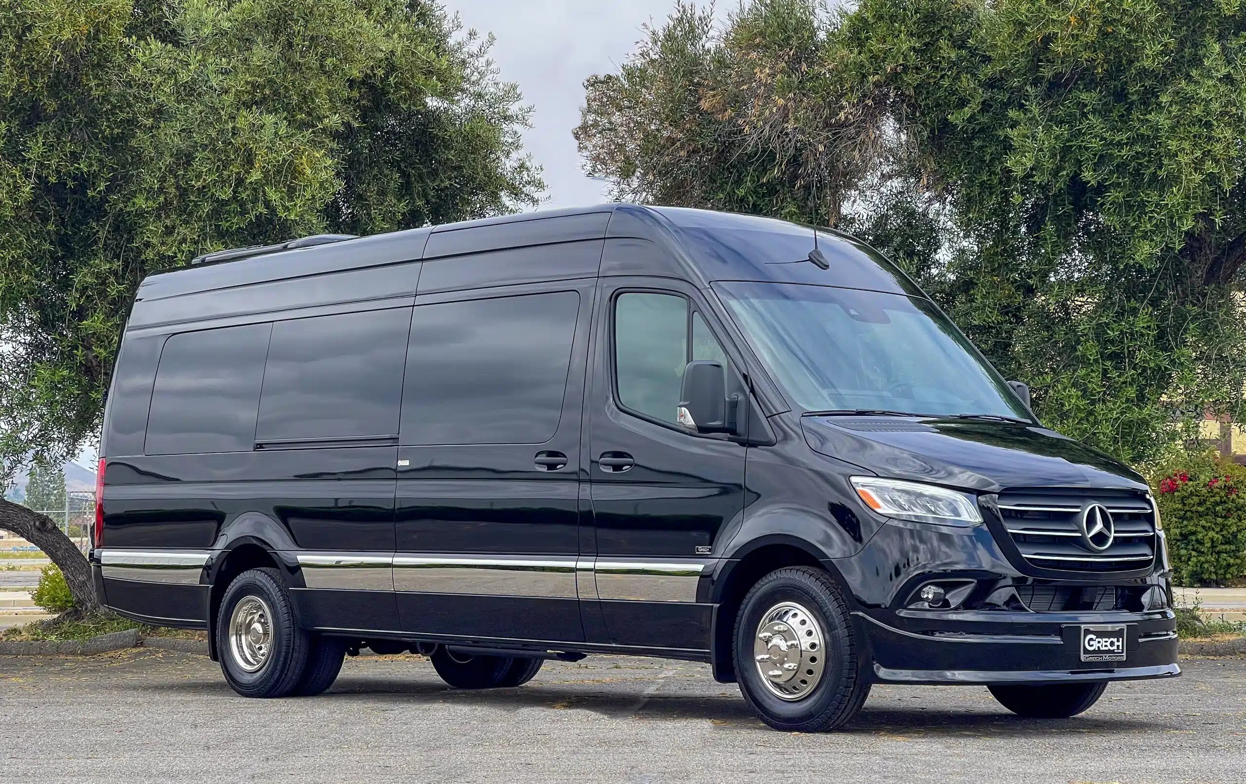 California Wine Tours black CWT luxury van parked beside historic stone wall in vineyard setting for wine tour travel