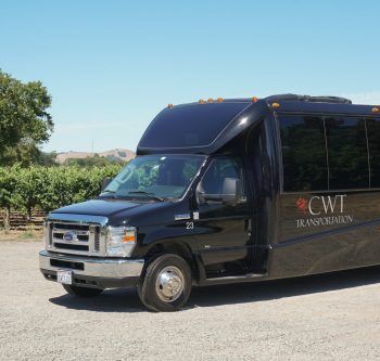California Wine Tours black CWT shuttle bus parked by vineyard road under clear blue sky for group wine tour transport
