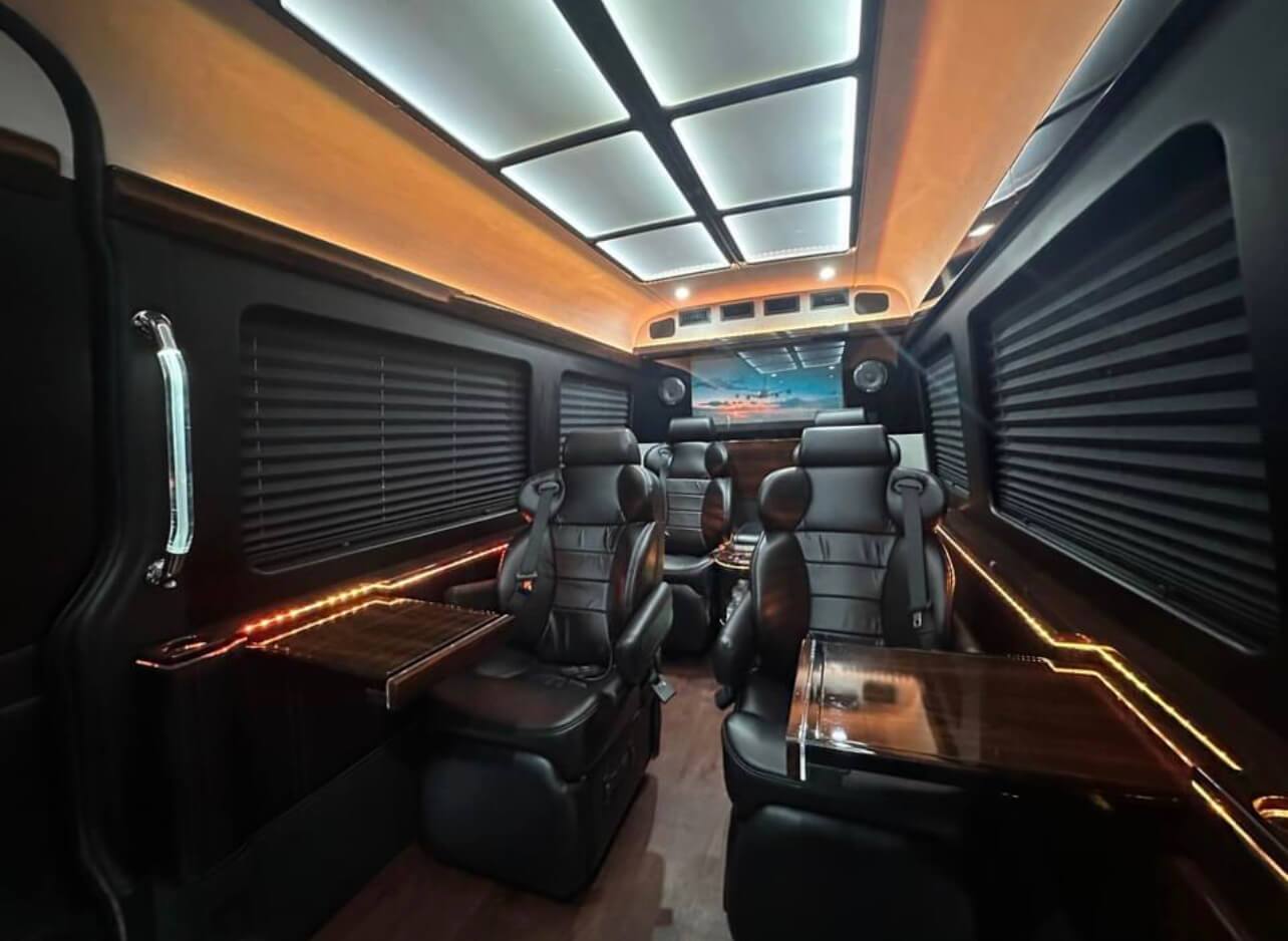 California Wine Tours luxury van cabin with reclining leather seats, wood tray tables, and modern ceiling lighting design
