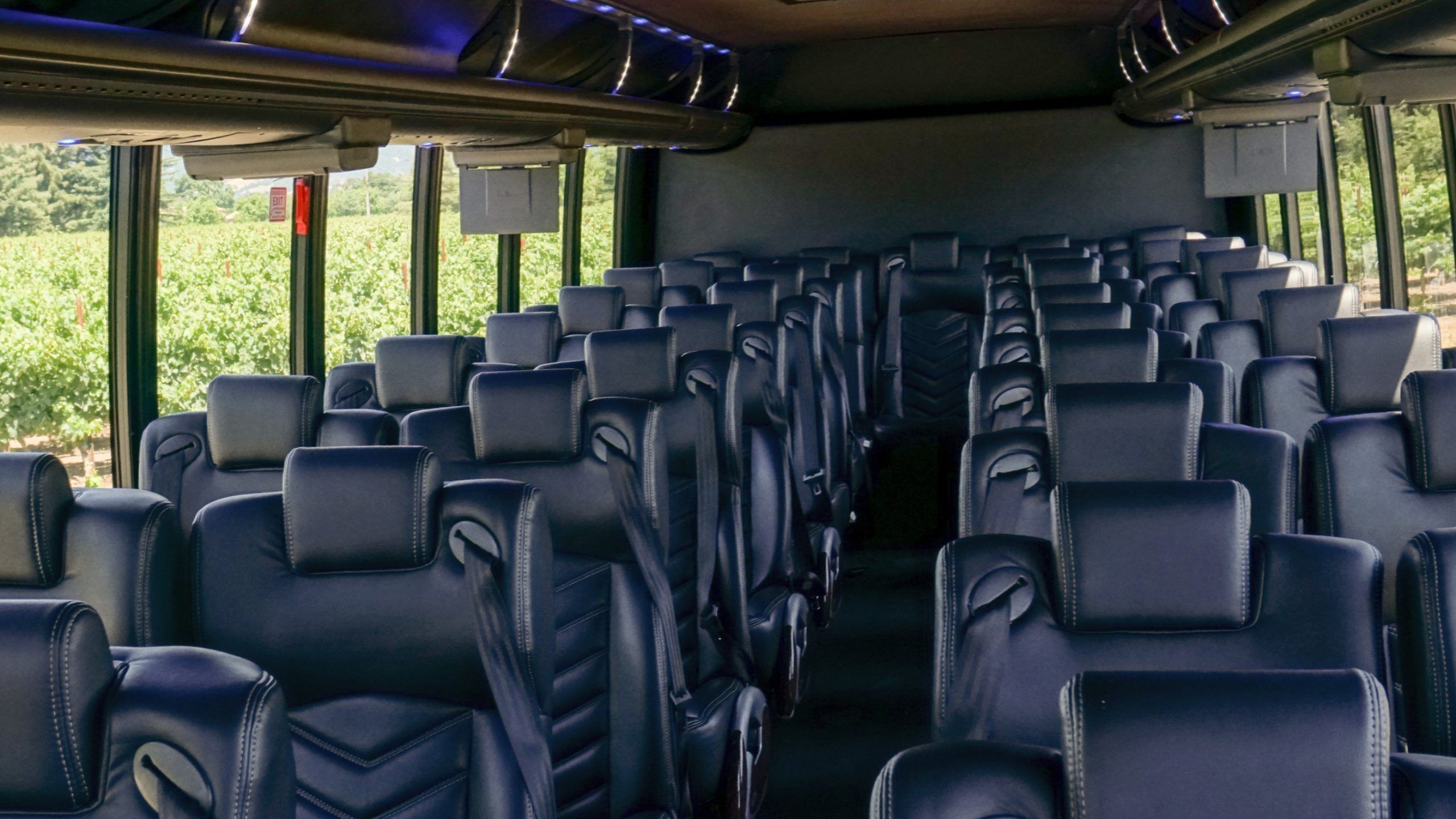 California Wine Tours motorcoach interior with rows of black leather seats and seatbelts, ready for group wine tour travel