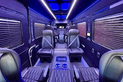 Luxury van interior with black leather seats, blue LED lighting, and spacious aisle seating.