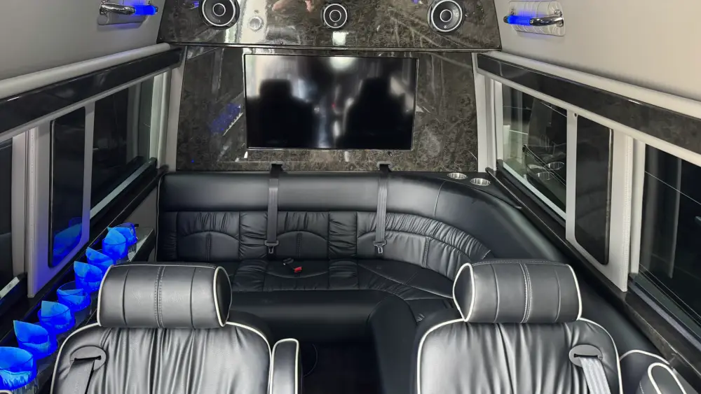 Luxury van lounge with wraparound black leather seating, flat screen, and ambient lighting for California Wine Tours guests