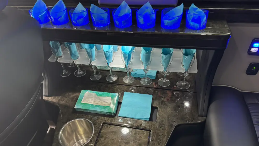 Blue-lit glassware and napkin setup inside California Wine Tours luxury shuttle, prepared for wine tasting group service