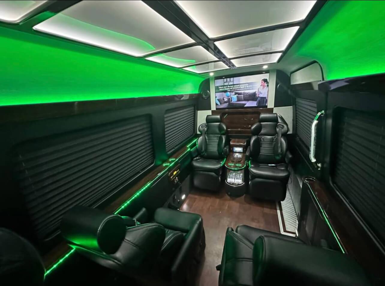 Luxury van interior with recliners, modern green LED lights, and entertainment system for upscale California Wine Tours.