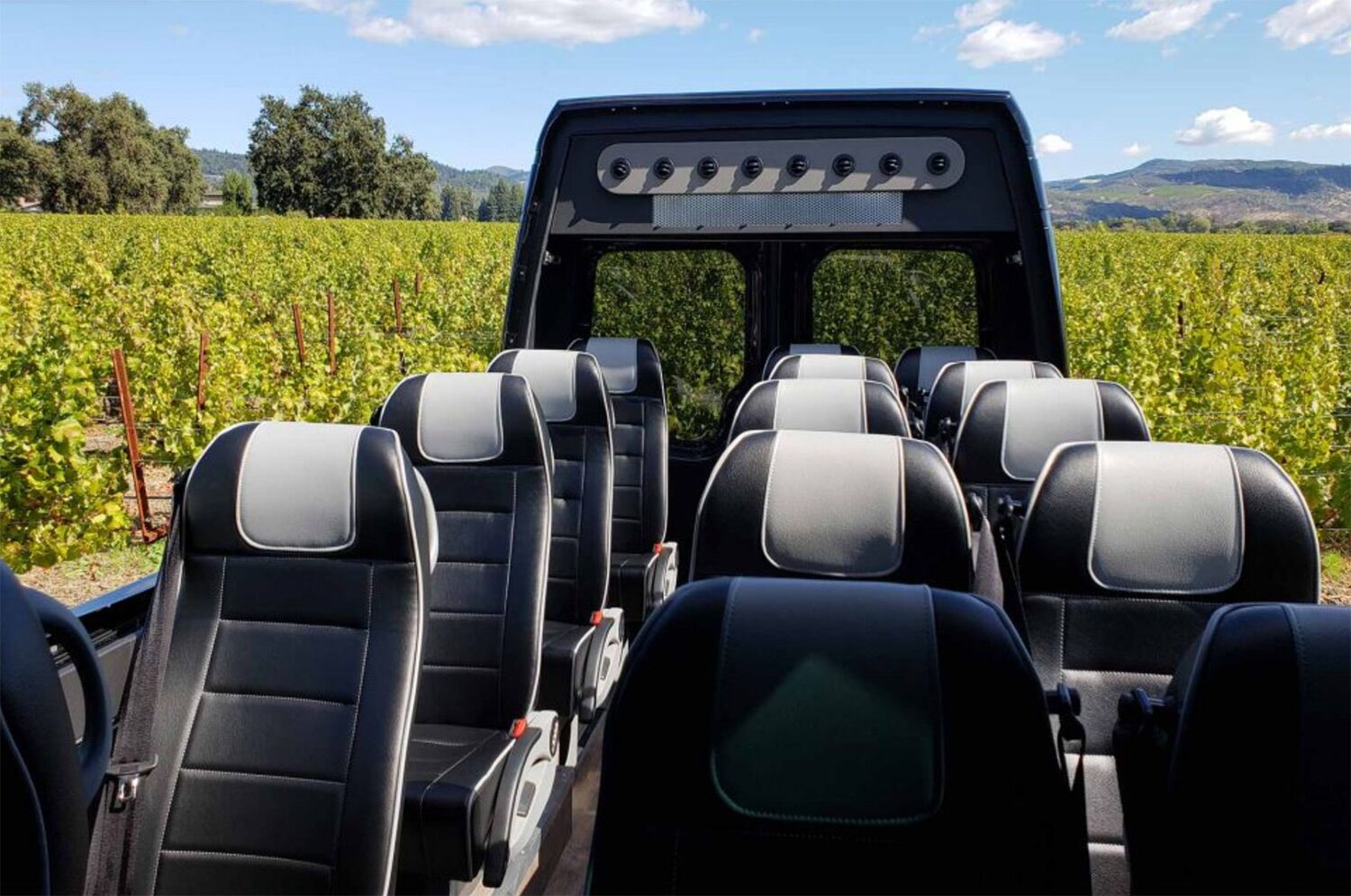 Black leather shuttle interior with vineyard views, used for luxury wine tours and corporate transportation in Napa Valley.