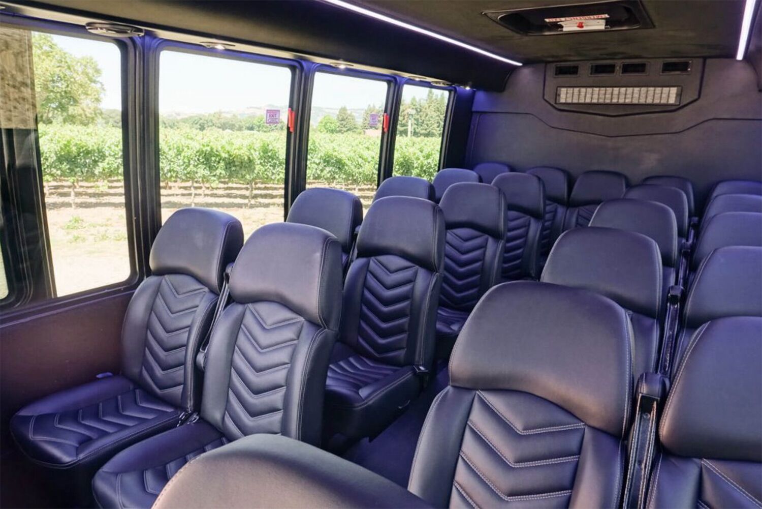Interior of black leather charter bus with rows of seats, used for corporate transportation in Napa Valley and wine tours.